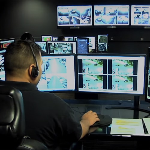 Person monitoring multiple security screens in a control room