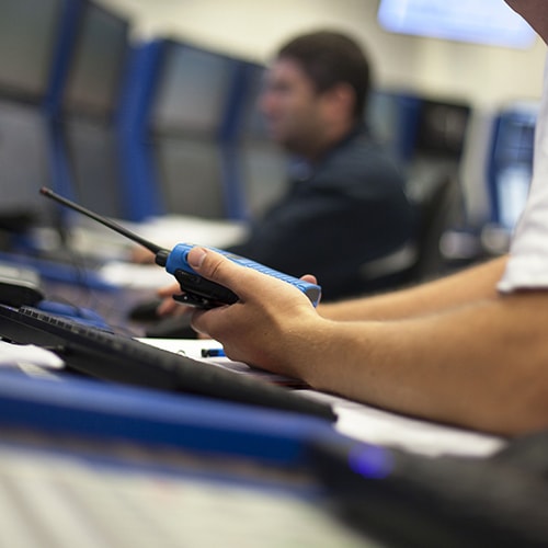 Person holding a walkie-talkie in an office setting with blurred background