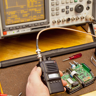 Electrical testing equipment on a workbench with a multimeter, oscilloscope, and digital display.